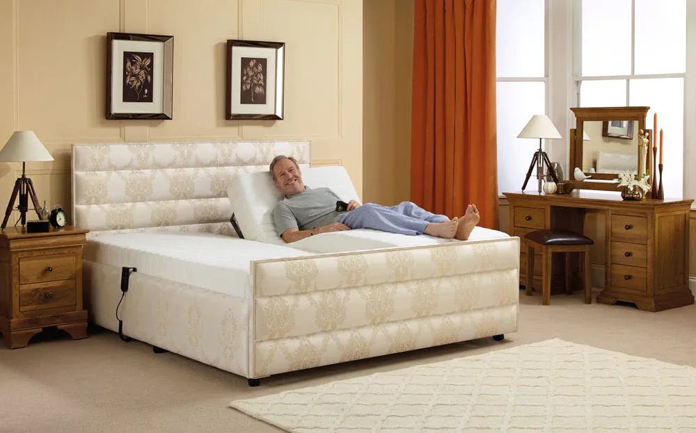 This image shows a man laying down on the reclined side of a double bed enjoying the custom bed.