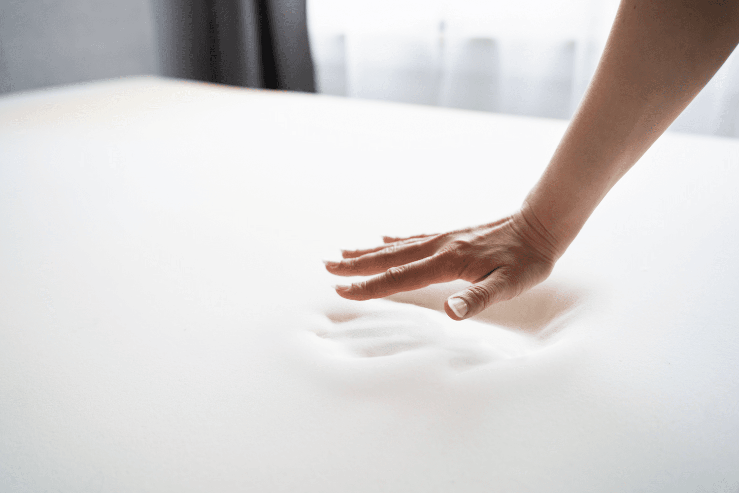 Hand pressing against mattress