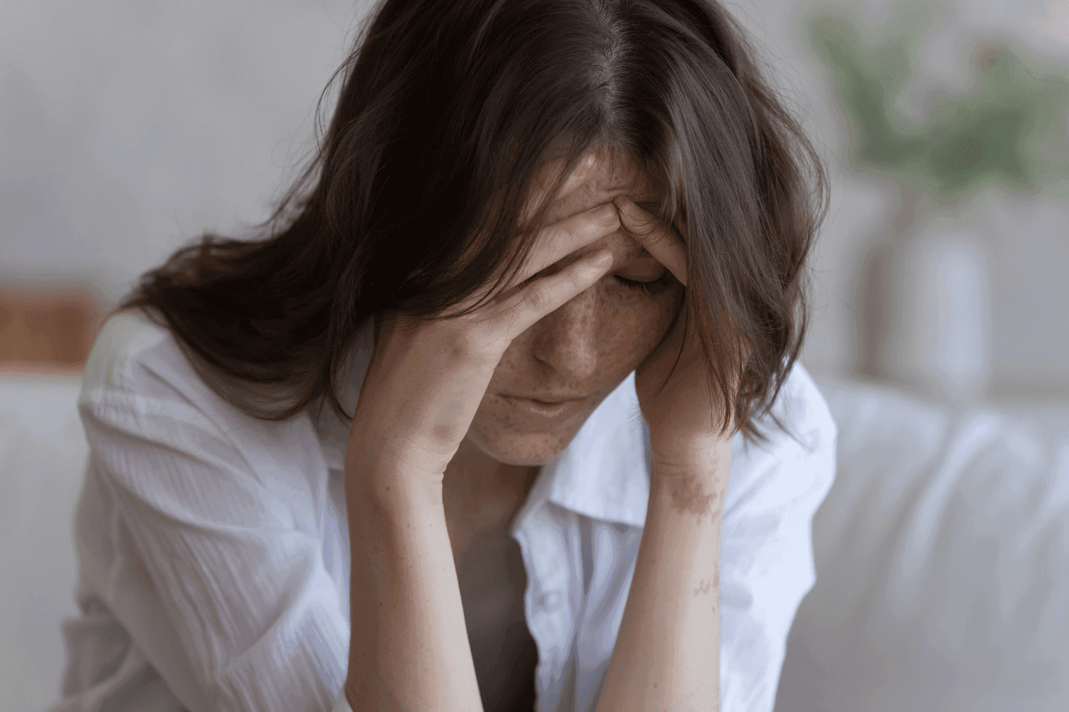 Image of woman with hands pressed against her head, due to a headache.