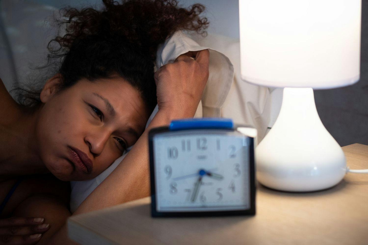 Woman looking at alarm clock unable to get back to sleep