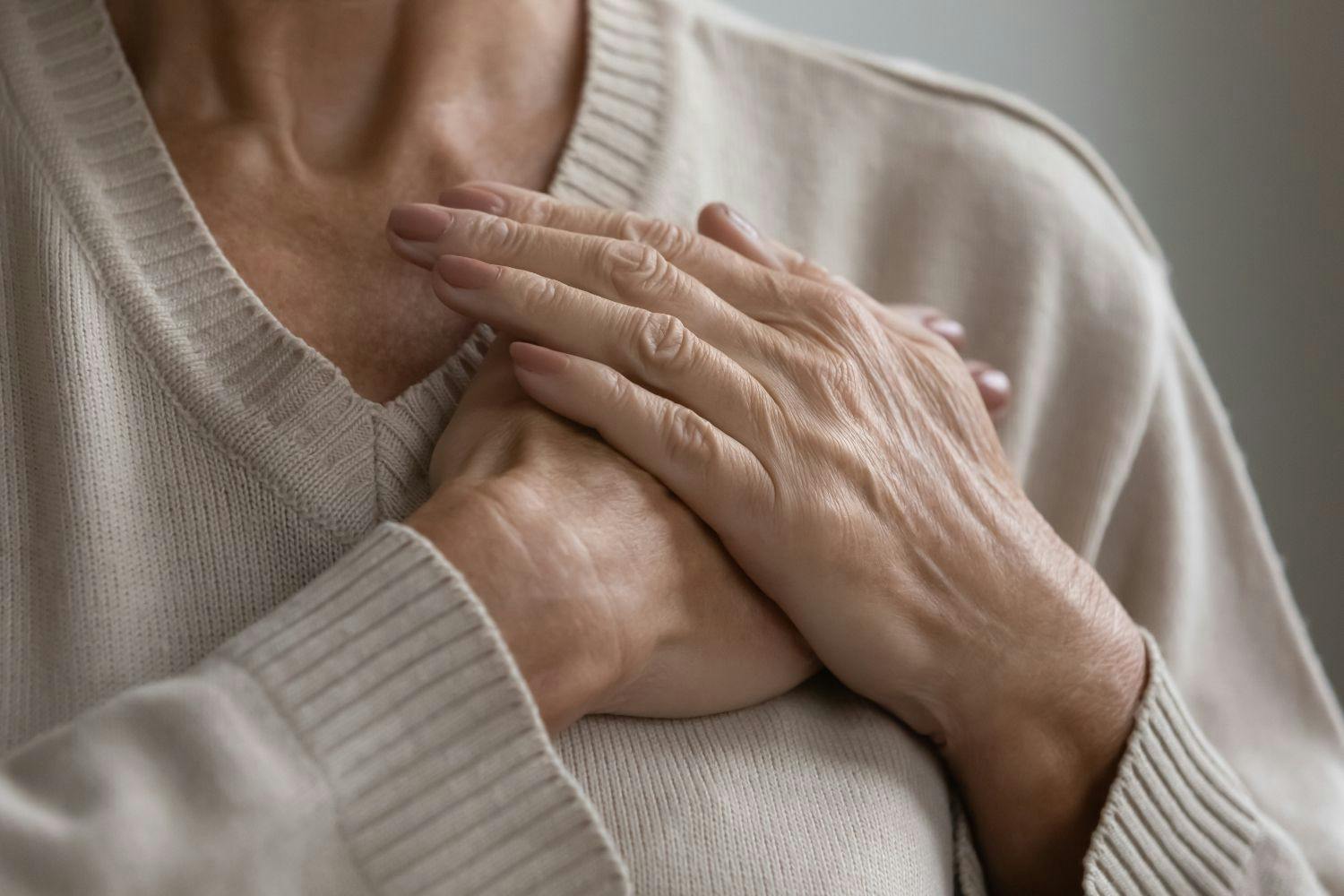 older woman placing hands over her heart