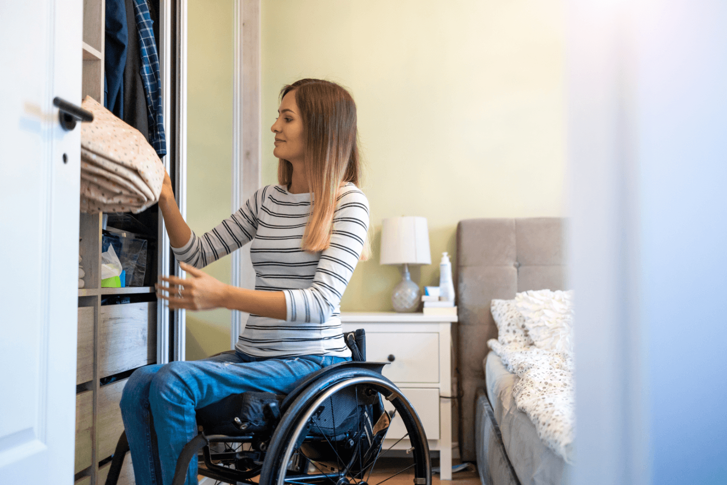 Woman using a wheelchair tidying her room