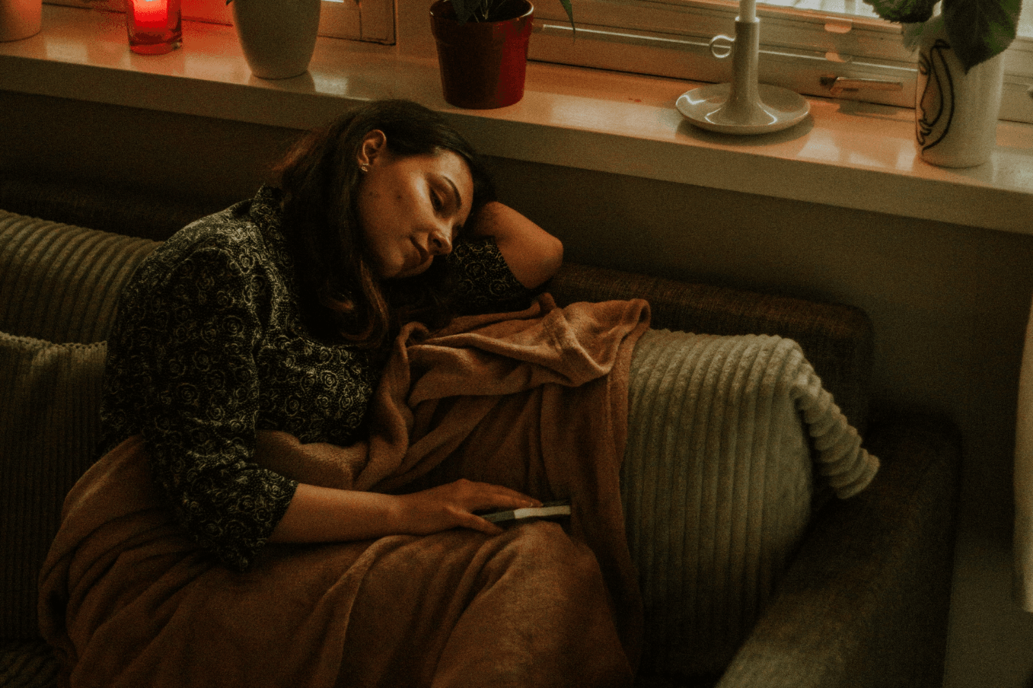 woman napping on a sofa with dimmed lights