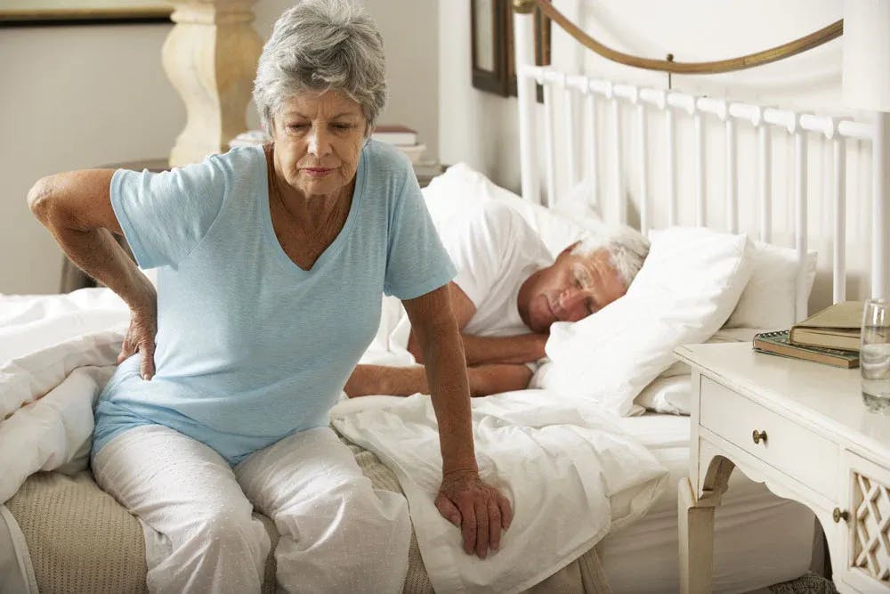 Woman getting out of bed with back pain