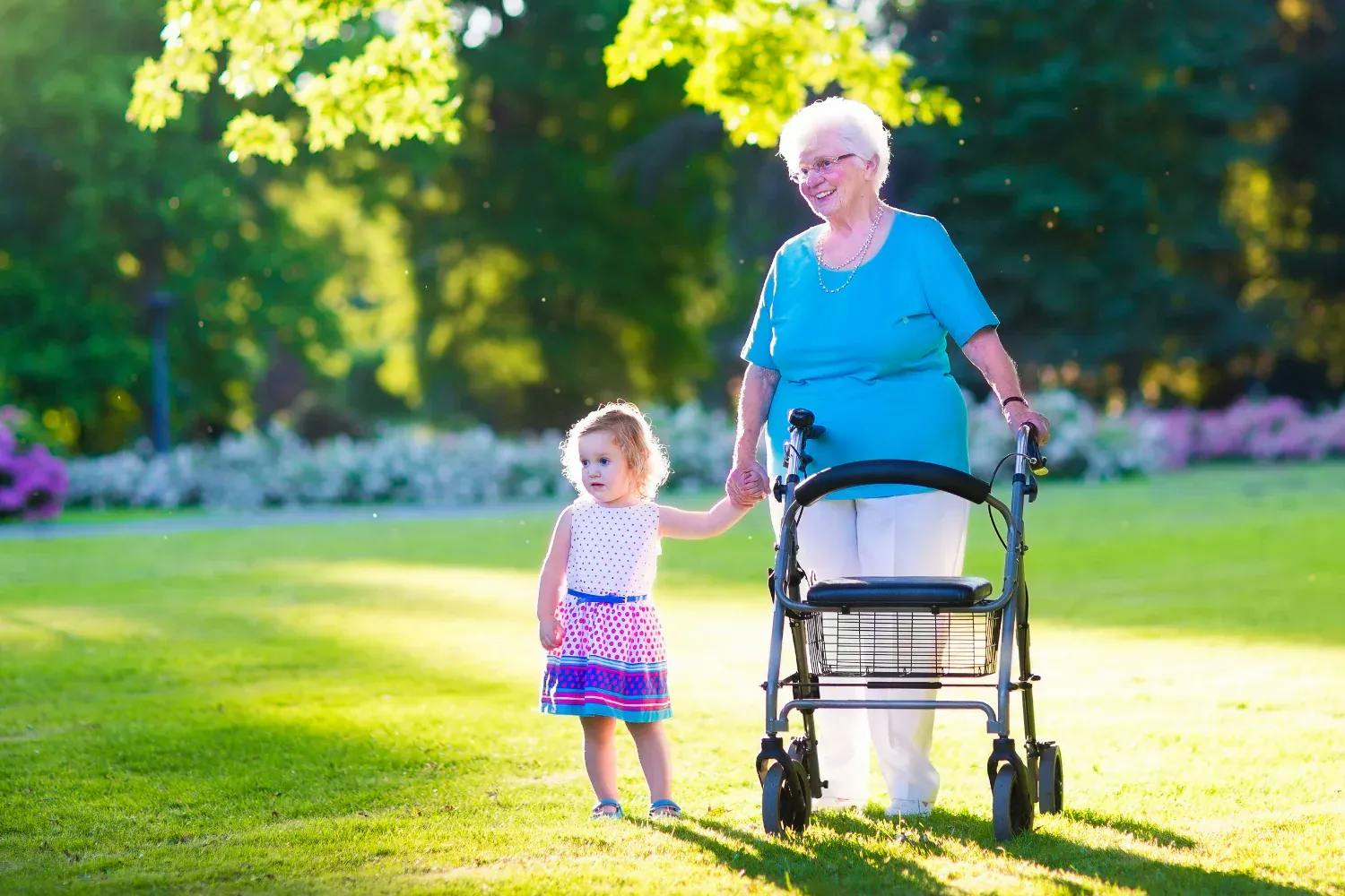 older woman using a walking aid to walk outside with their grandchild