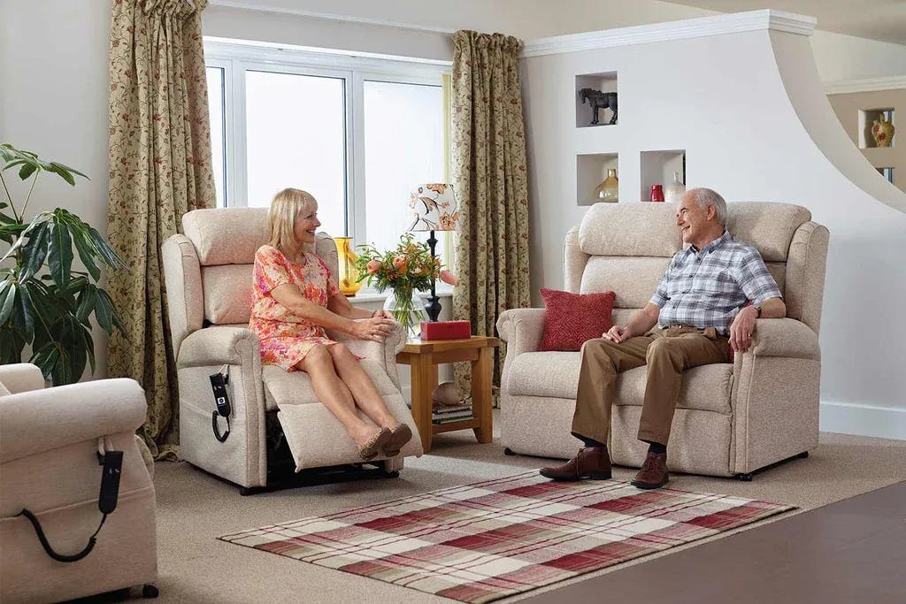 Elderly couple sitting on two fabric reclining chairs
