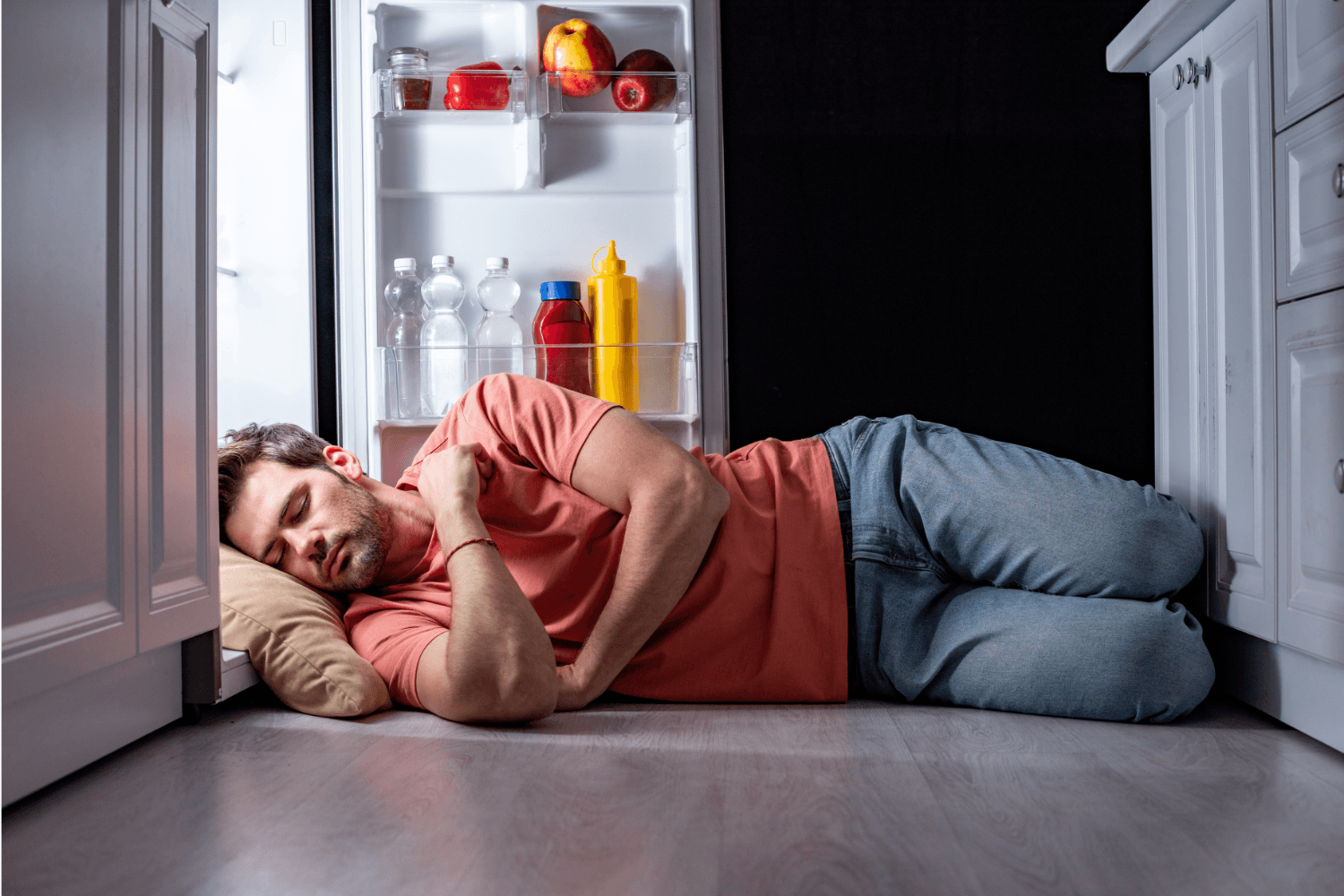 Man sleeping near fridge because they're too hot