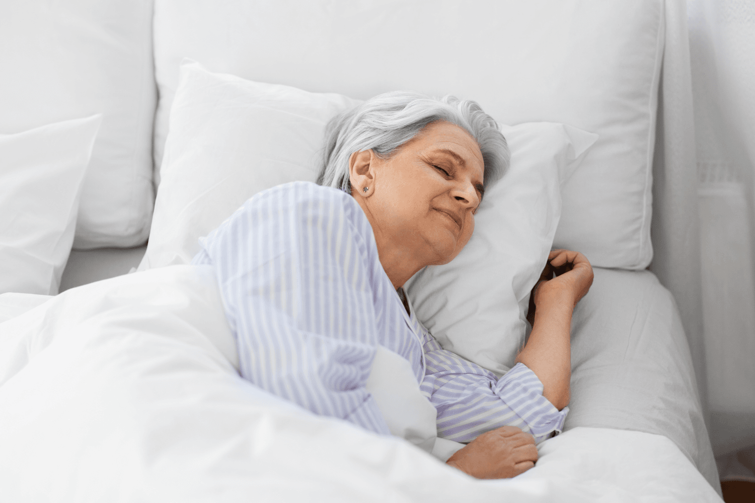 woman sleeping in bed with white sheets and wearing a blue shirt