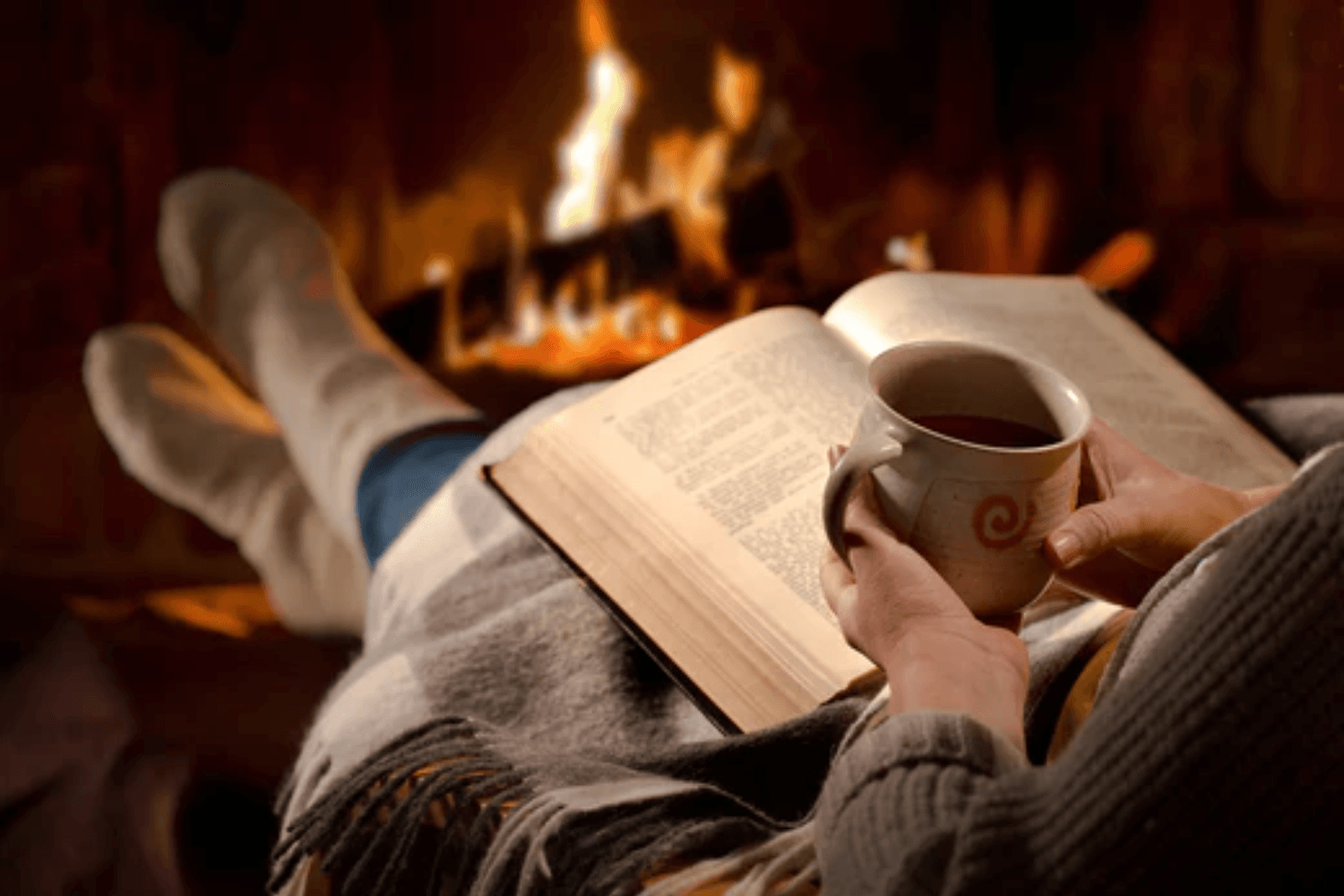 Woman reading next to a fire