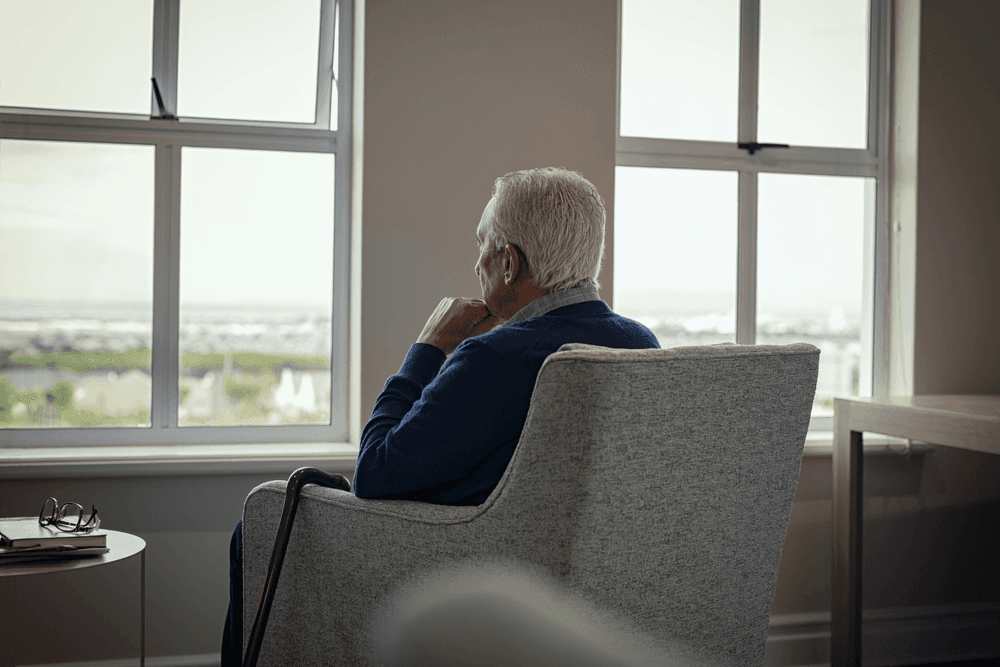 Image of elderly gentleman faced towards window looking out.