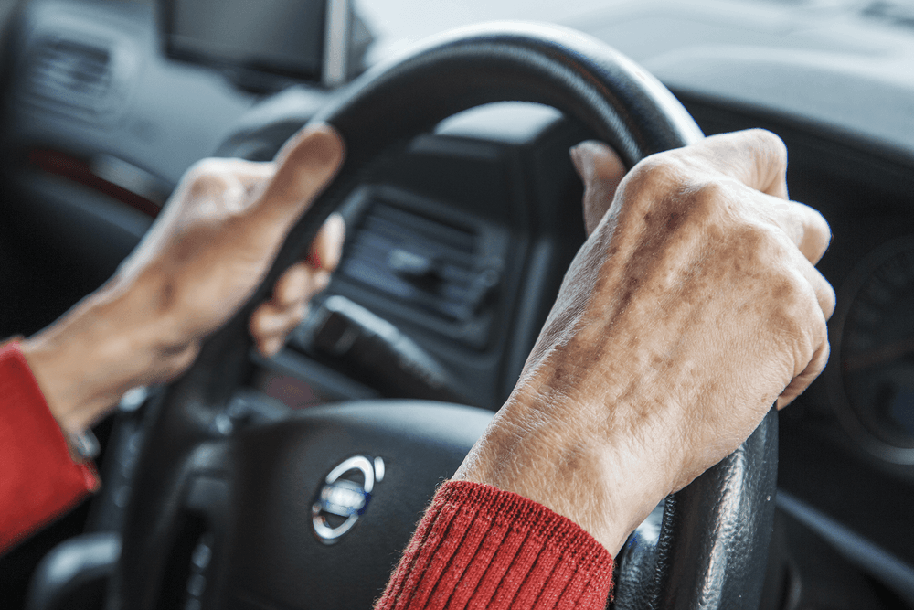 Close up of older woman hands placed on steering wheel