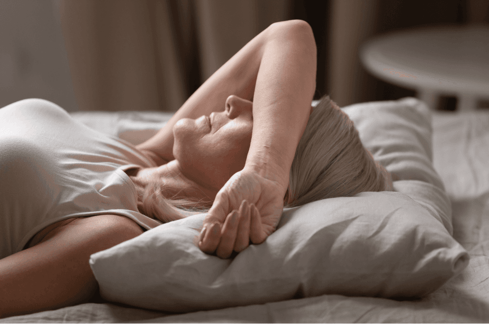 Older woman in bed in the morning, arm covering face